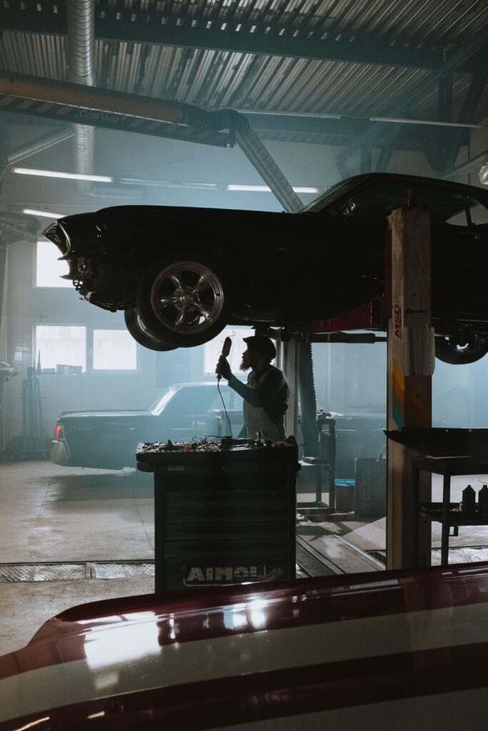 Mecanico inspeccionando vehiculo elevado en taller